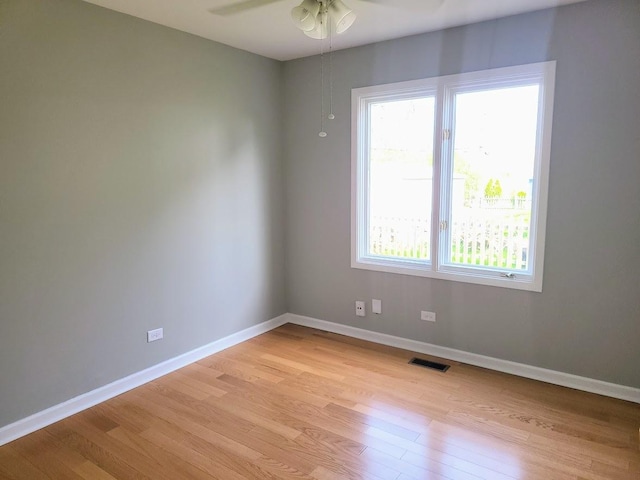 empty room featuring visible vents, a ceiling fan, light wood-style flooring, and baseboards