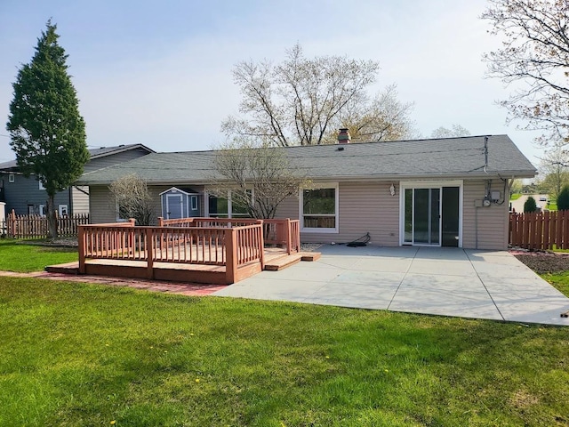 rear view of property with fence, a wooden deck, a chimney, a patio area, and a lawn