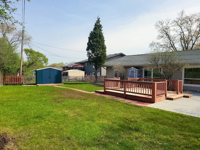 view of yard featuring an outdoor structure, a shed, a wooden deck, and fence