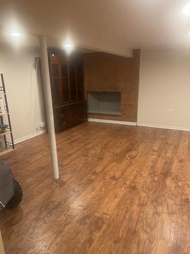 basement featuring baseboards, a fireplace, and wood finished floors