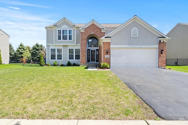 traditional-style home featuring brick siding, fence, aphalt driveway, a garage, and a front yard