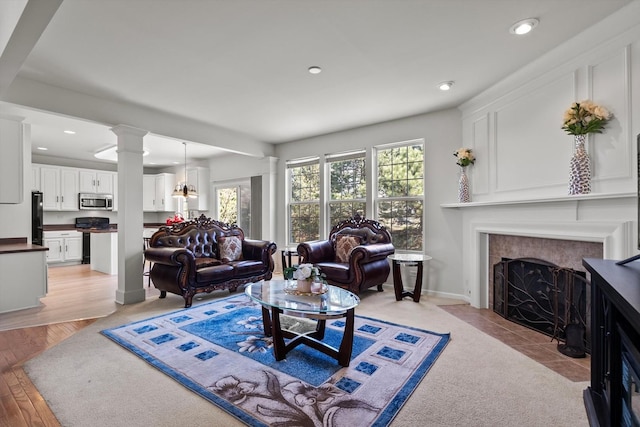 living room with recessed lighting, a fireplace with flush hearth, and decorative columns