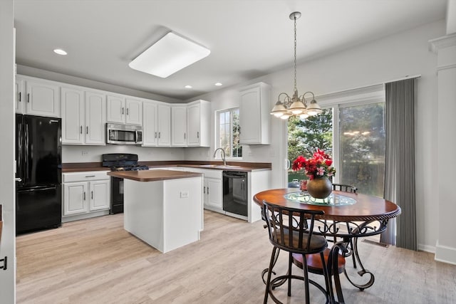 kitchen with black appliances, white cabinetry, light wood-type flooring, and a center island