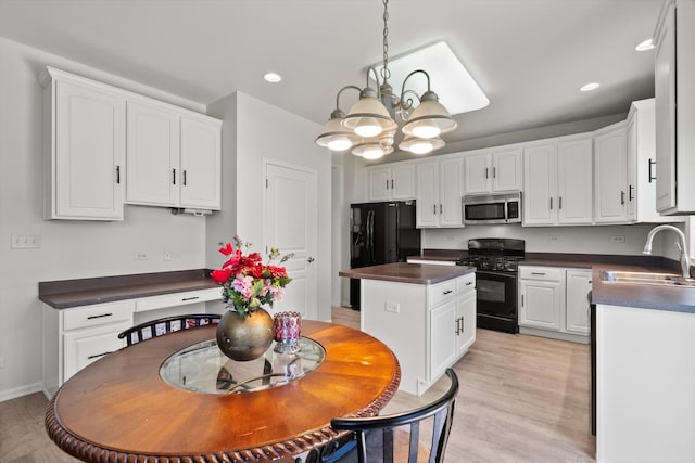 kitchen featuring white cabinets, a sink, dark countertops, black appliances, and a notable chandelier