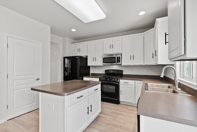 kitchen with white cabinets, a sink, dark countertops, a kitchen island, and black appliances