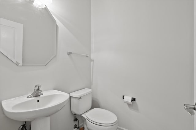 bathroom with toilet, baseboards, and a sink