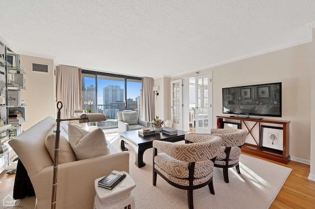 living area with light wood-style floors, a textured ceiling, and visible vents