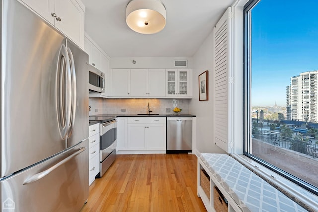 kitchen featuring visible vents, tasteful backsplash, a sink, light wood-style floors, and stainless steel appliances