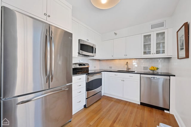 kitchen with visible vents, dark countertops, appliances with stainless steel finishes, tasteful backsplash, and light wood-style flooring