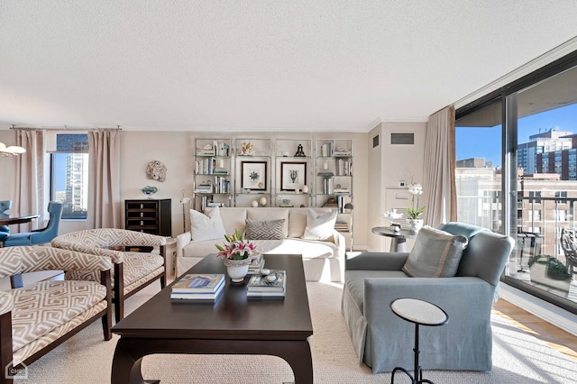 living area with a textured ceiling, visible vents, and wood finished floors