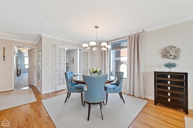 dining space with light wood-style floors, a textured ceiling, a chandelier, and a wealth of natural light