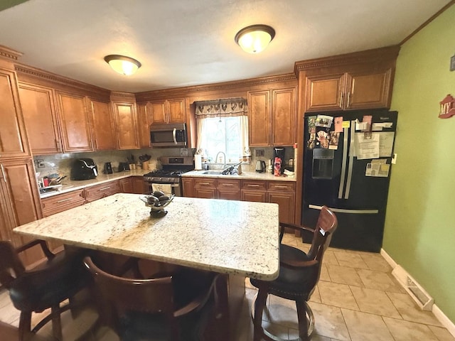 kitchen with a sink, appliances with stainless steel finishes, a breakfast bar, and tasteful backsplash