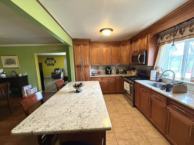 kitchen featuring crown molding, a sink, brown cabinetry, stainless steel appliances, and backsplash