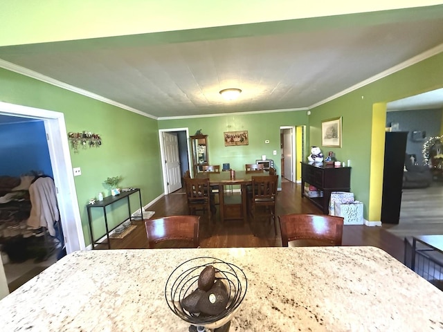 dining space with crown molding, baseboards, and wood finished floors