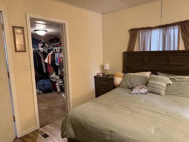 bedroom featuring visible vents, crown molding, wood finished floors, a closet, and a spacious closet