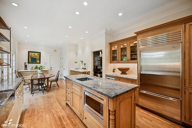 475 Maple St, Winnetka, IL 60093 - kitchen with built in appliances, a center island with sink, brown cabinets, light wood finished floors, and recessed lighting