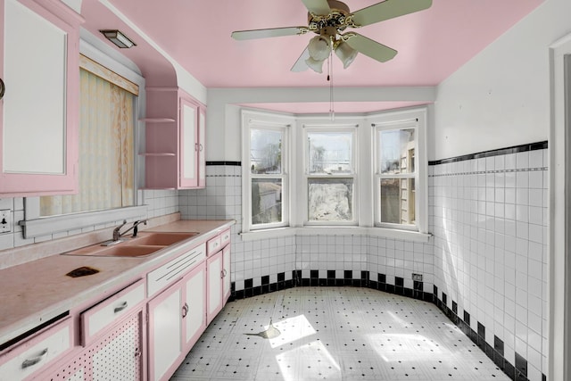 3134 N Mason Ave, Chicago, IL 60634 - kitchen with a sink, tile walls, light countertops, white cabinets, and a ceiling fan