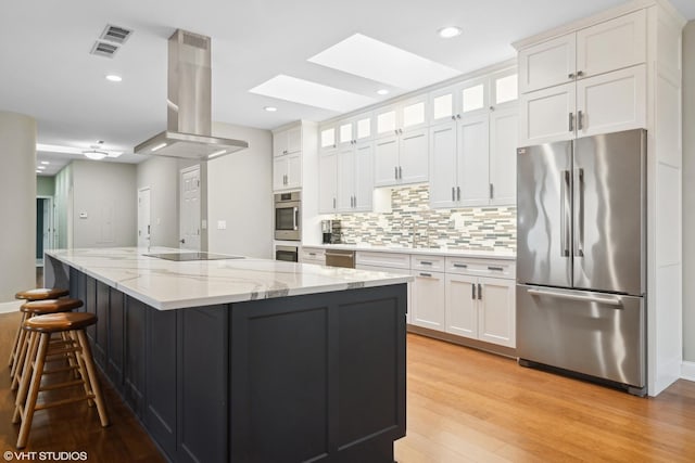 1 Renaissance Pl Unit 1Ph, Palatine, IL 60067 - kitchen with appliances with stainless steel finishes, a skylight, island exhaust hood, white cabinetry, and backsplash