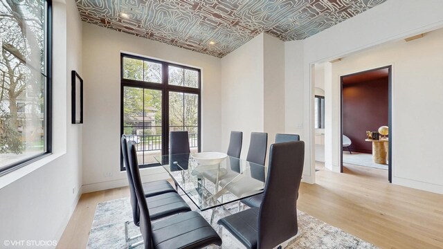 dining area featuring light wood finished floors, an ornate ceiling, and baseboards