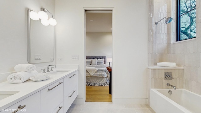 ensuite bathroom with double vanity, connected bathroom, tile patterned floors, and a sink