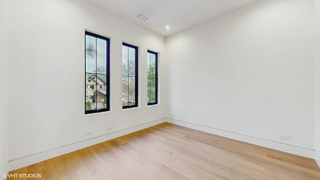 spare room featuring light wood-type flooring, recessed lighting, and baseboards