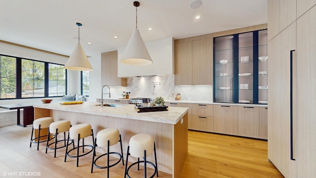 kitchen featuring a sink, modern cabinets, light brown cabinets, light wood-style flooring, and light countertops