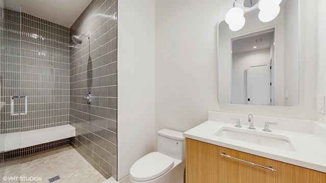 bathroom featuring toilet, a tile shower, and vanity