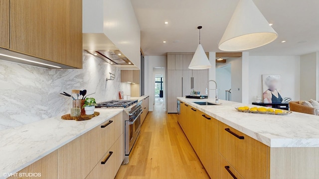 kitchen featuring light wood-style flooring, high end stainless steel range, extractor fan, a sink, and modern cabinets