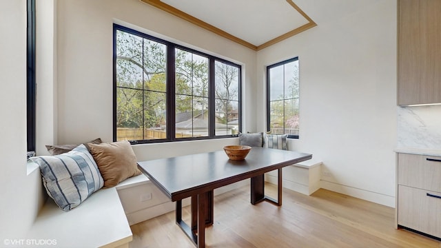 dining space with baseboards, light wood-type flooring, and crown molding