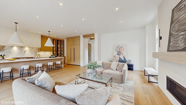 living area with light wood-type flooring, recessed lighting, and a glass covered fireplace