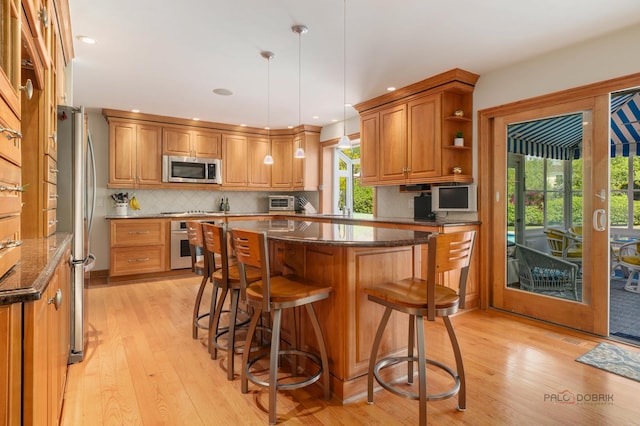 1878 Hackberry Ln, Lake Forest, IL 60045 - kitchen featuring appliances with stainless steel finishes, a kitchen island, dark stone countertops, light wood-type flooring, and recessed lighting