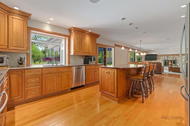 1878 Hackberry Ln, Lake Forest, IL 60045 - kitchen featuring appliances with stainless steel finishes, a sink, open floor plan, light wood finished floors, and brown cabinets