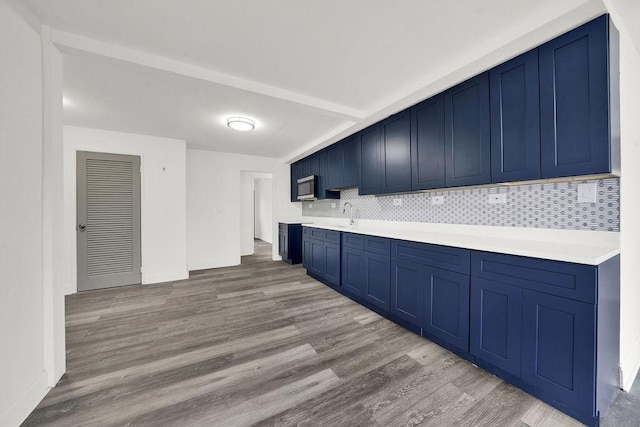 1401 Stanley Blvd, Calumet City, IL 60409 - kitchen with light countertops, stainless steel microwave, decorative backsplash, wood finished floors, and blue cabinets