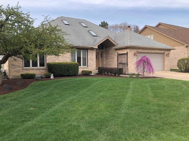 ranch-style home featuring a chimney, a front lawn, driveway, brick siding, and a garage
