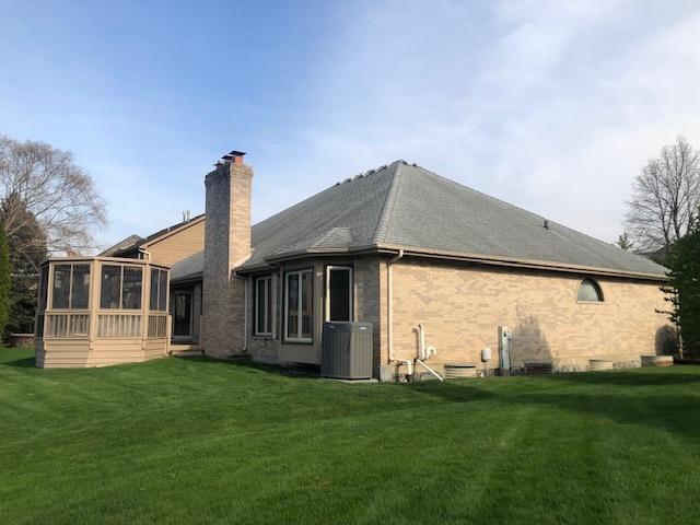 back of house with a chimney, a yard, central AC, brick siding, and a sunroom