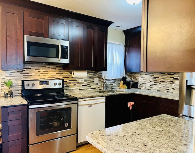 kitchen with stainless steel appliances, light stone countertops, and a sink
