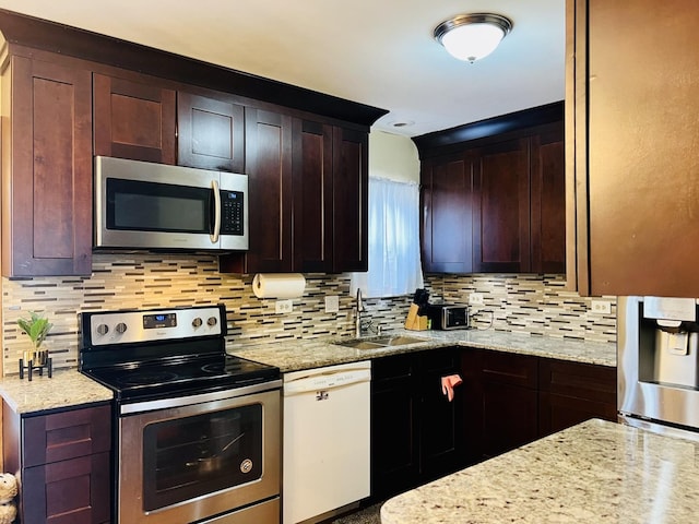 kitchen with light stone counters, tasteful backsplash, stainless steel appliances, and a sink