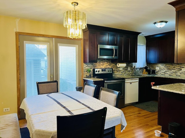 kitchen with a chandelier, light wood-style floors, stainless steel appliances, and tasteful backsplash