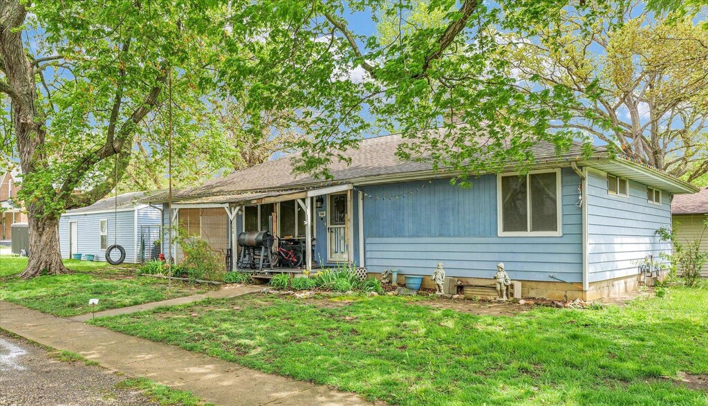 ranch-style home with roof with shingles and a front yard