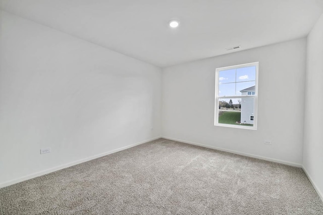 carpeted empty room featuring baseboards and visible vents