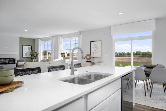 kitchen featuring a sink, dishwasher, white cabinetry, dark wood-type flooring, and recessed lighting