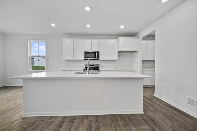 kitchen featuring white cabinetry, stainless steel appliances, light countertops, and an island with sink