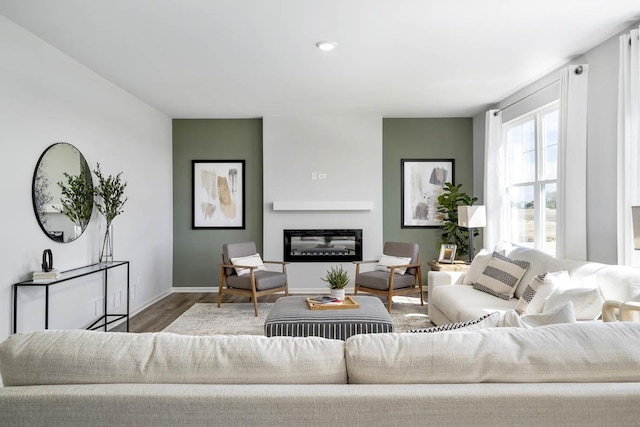living area with recessed lighting, baseboards, wood finished floors, and a glass covered fireplace