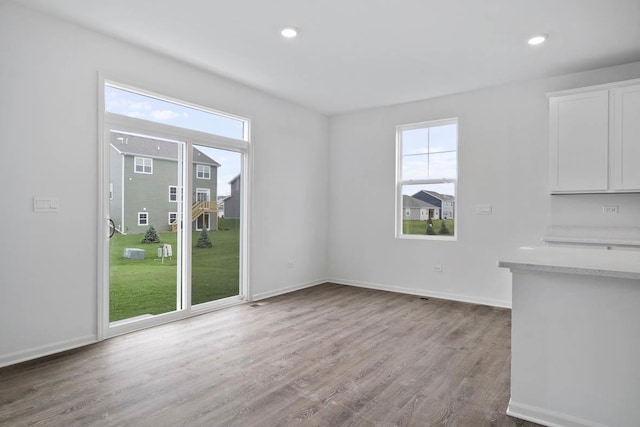 unfurnished dining area featuring recessed lighting, wood finished floors, and baseboards
