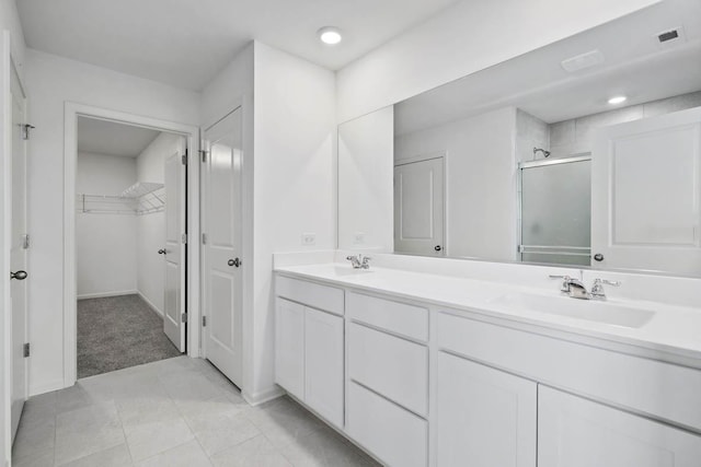 bathroom featuring double vanity, a sink, a shower stall, and a spacious closet