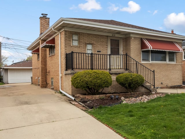 bungalow with a front yard, an outbuilding, a chimney, a detached garage, and brick siding