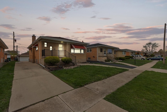 bungalow featuring a chimney, a front yard, brick siding, and a garage