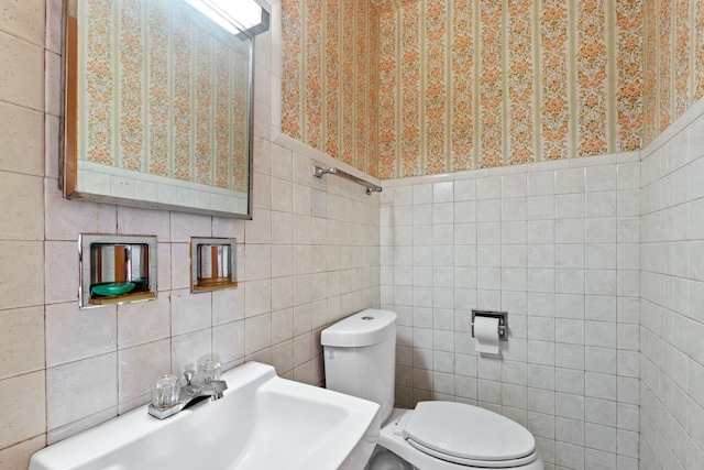 bathroom featuring a sink, toilet, and tile walls