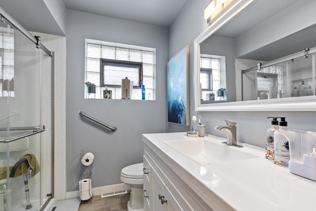 bathroom featuring a shower stall, vanity, toilet, visible vents, and wood finished floors