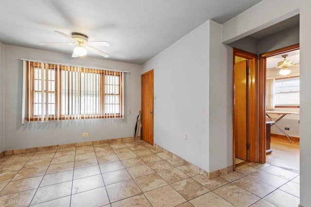 unfurnished room featuring baseboards, light tile patterned floors, and ceiling fan